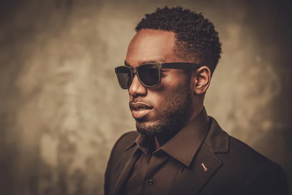 Smiling young black man with sunglasses posing on dark background. — Stock Photo, Image