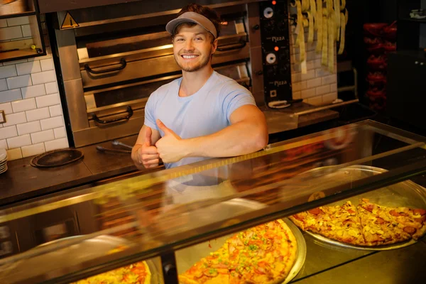Schöner Pizzaiolo steht in der Küche einer Pizzeria. — Stockfoto