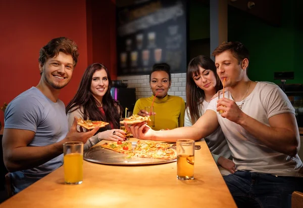 Amigos multirraciais se divertindo comendo pizza na pizzaria . — Fotografia de Stock