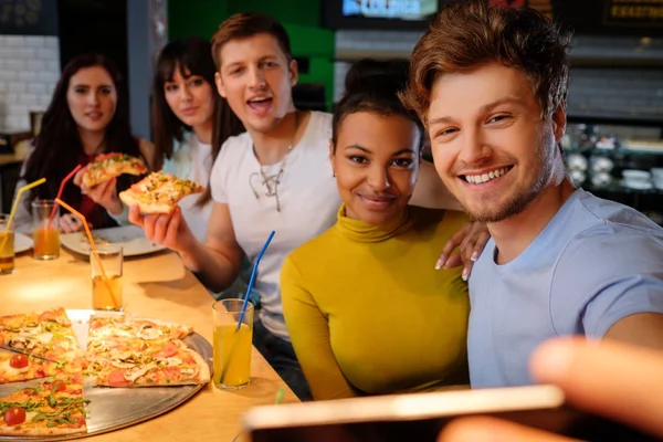 Multiracial vänner ha roligt äta pizza på pizzeria. — Stockfoto