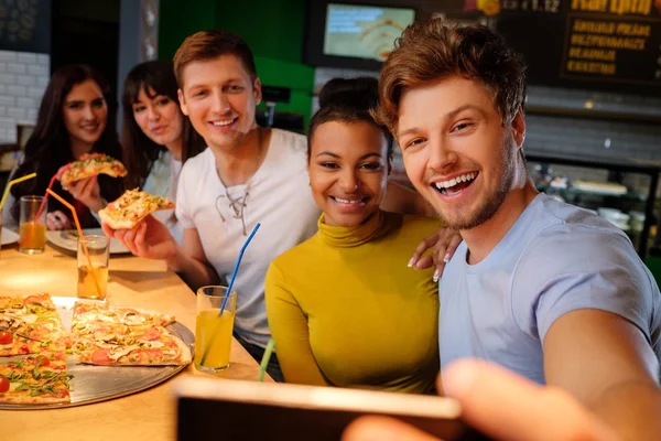 Wielorasowe znajomi, zabawa jedzenie pizzy w pizzerii. — Zdjęcie stockowe