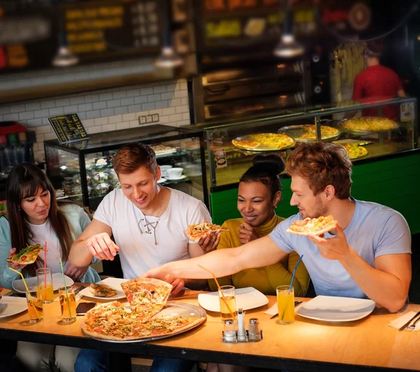 Mnohonárodnostní přátel bavit jíst pizzu v pizzerii. — Stock fotografie
