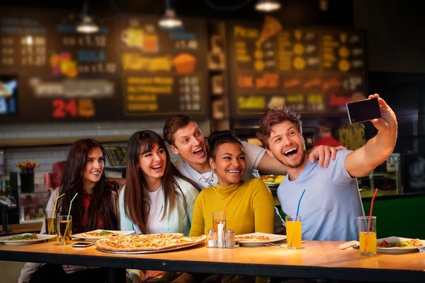 Multiracial vänner ha roligt äta pizza på pizzeria. — Stockfoto