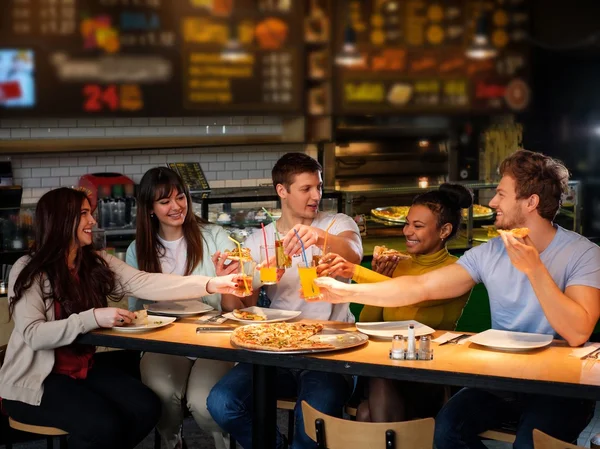 Amici multirazziali si divertono a mangiare pizza in pizzeria . — Foto Stock