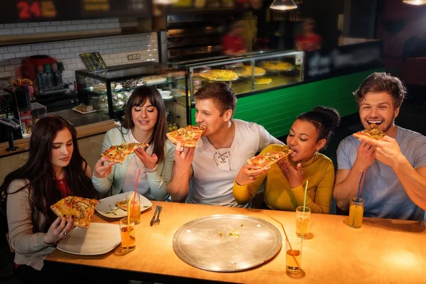 Multiracial vänner ha roligt äta pizza på pizzeria. — Stockfoto