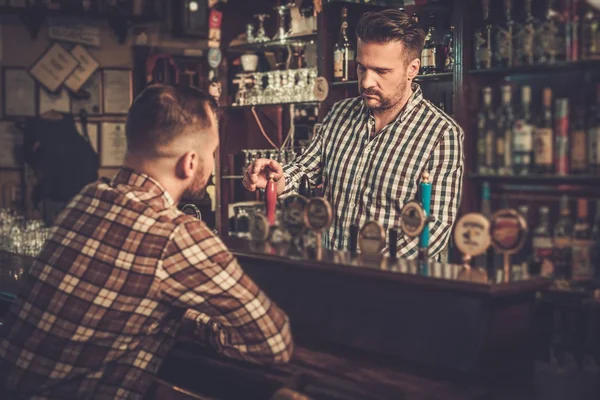 Pohledný barman sklenku piva k zákazníkovi v hospodě. — Stock fotografie