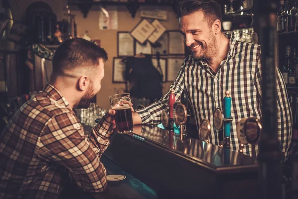Bel barista che versa una pinta di birra al cliente in un pub . — Foto Stock
