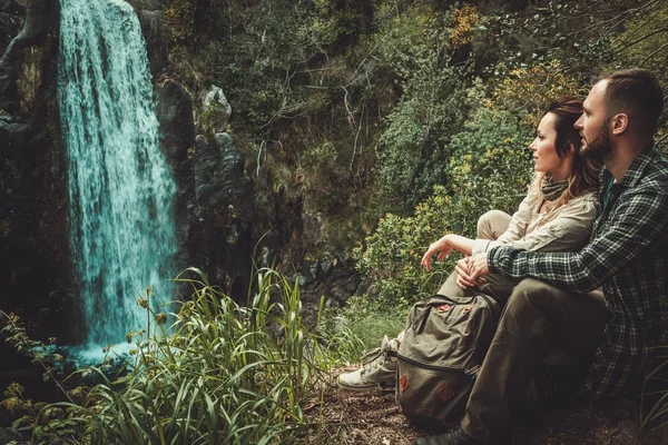 Beautiful woman hiker sitting near waterfall in deep forest. — Stock Photo, Image