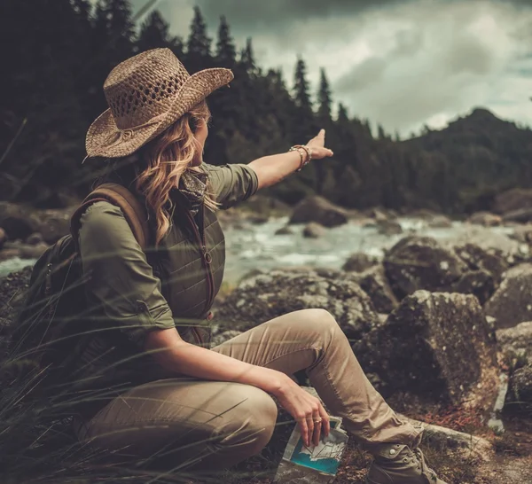 Femme randonneur, à la recherche dans la bonne direction sur la carte près de la rivière sauvage de montagne . — Photo