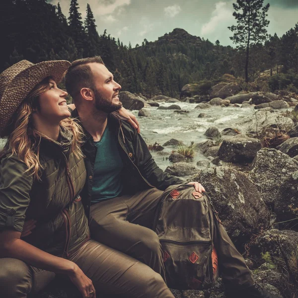 Casal caminhantes sentados perto do rio montanha selvagem . — Fotografia de Stock