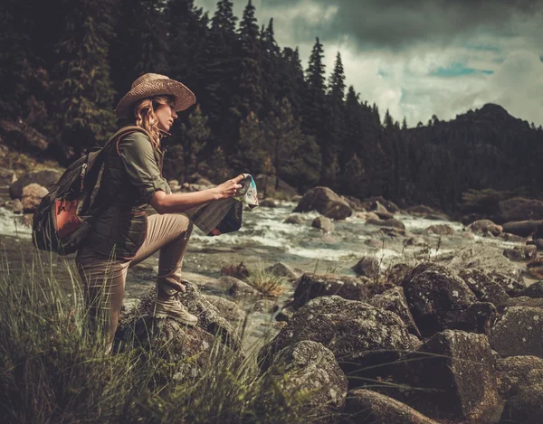 Kadın hiker, vahşi dağ Nehri yakınında haritada doğru yönde arama. — Stok fotoğraf