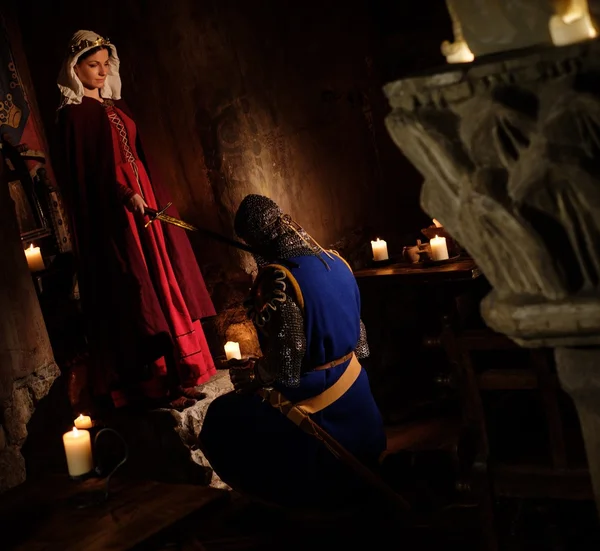 Medeltida drottning gör knighting ceremoni i gamla slottet interiören. — Stockfoto