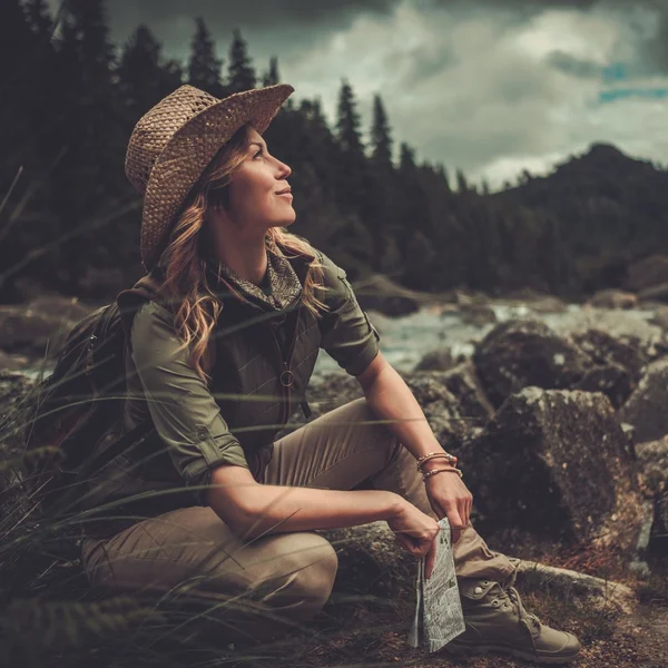 Smiling woman hiker, sitting with map in her hands — Stock Photo, Image