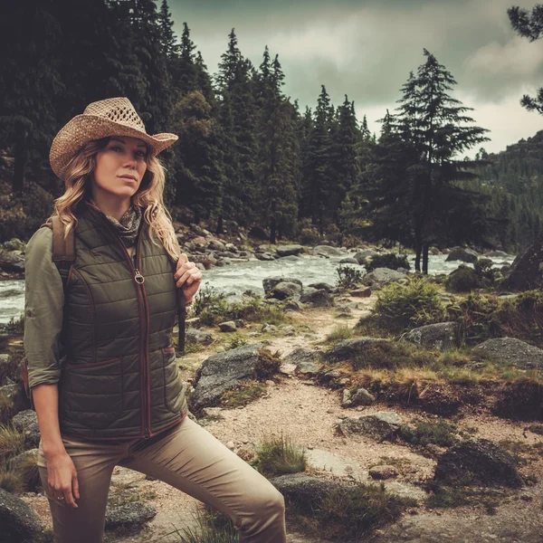 Hermosa mujer excursionista disfrutando de paisajes increíbles cerca del río salvaje de montaña . — Foto de Stock