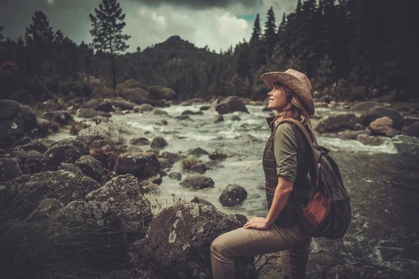 Mulher bonita caminhante desfrutando de paisagens incríveis perto de rio de montanha selvagem . — Fotografia de Stock