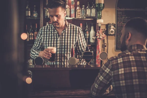 Barista versando una pinta di birra al cliente in un pub . — Foto Stock