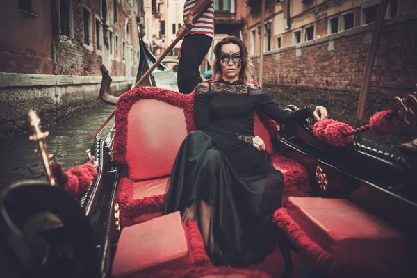 Donna in abito nero con maschera carnavale cavalcando in gondola . — Foto Stock