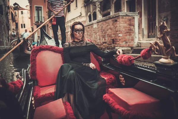 Woman in black dress with carnaval mask riding on gondola. — Stock Photo, Image