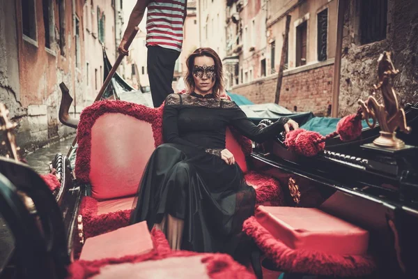 Woman in black dress with carnaval mask riding on gondola. — Stock Photo, Image