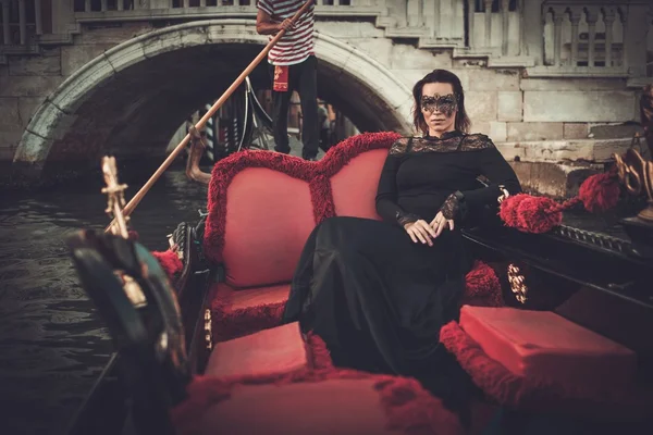 Donna in abito nero con maschera carnavale cavalcando in gondola . — Foto Stock