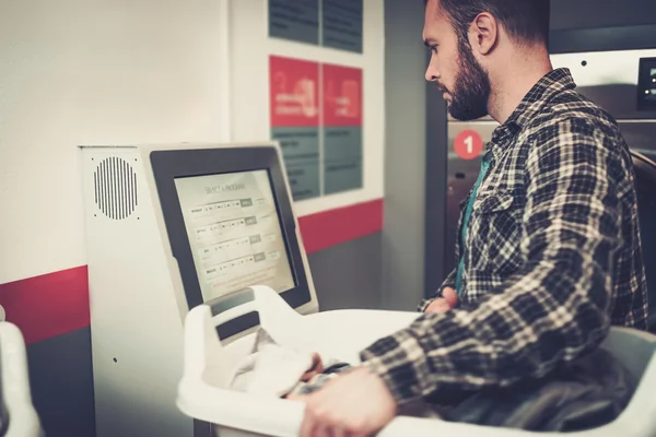 Handsome man doing laundry at laundromat shop. — Stock Photo, Image