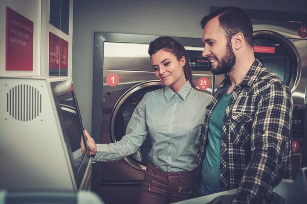 Junges fröhliches Paar beim gemeinsamen Wäschewaschen im Waschsalon. — Stockfoto