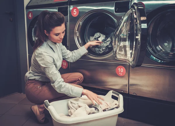 Vacker kvinna gör tvätt på laundromat shop. — Stockfoto