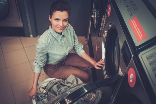 Vacker kvinna gör tvätt på laundromat shop. — Stockfoto