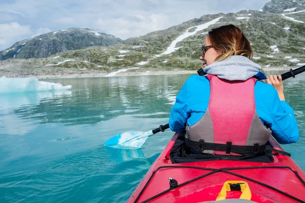 Žena na kajaku na Styggvatnet ledovcovém jezeře poblíž ledovec Jostedalsbreen. — Stock fotografie