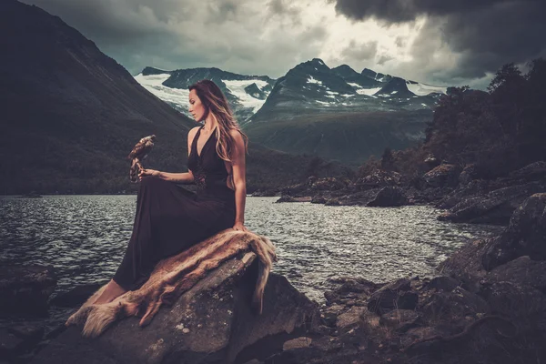 Nordische Göttin in rituellem Gewand mit Habicht am wilden Bergsee im Inntal. — Stockfoto