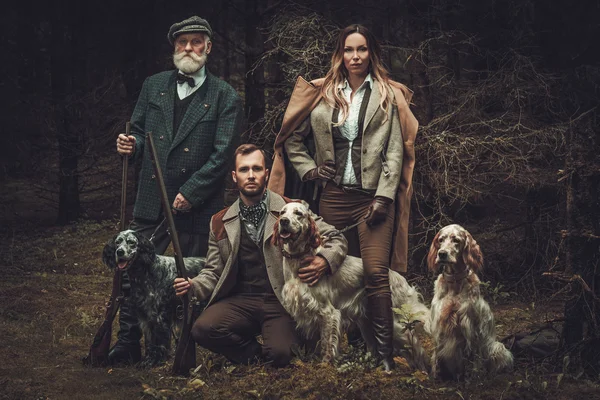 Ryhmä monen ikäisiä metsästäjiä koirien ja haulikoiden kanssa — kuvapankkivalokuva