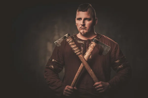 Viking sério com machados em uma roupa de guerreiro tradicional — Fotografia de Stock