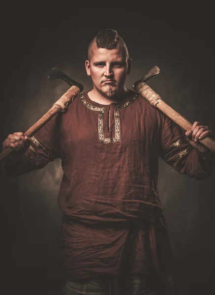 Серьезный викинг с топорами в традиционной одежде воина — стоковое фото
