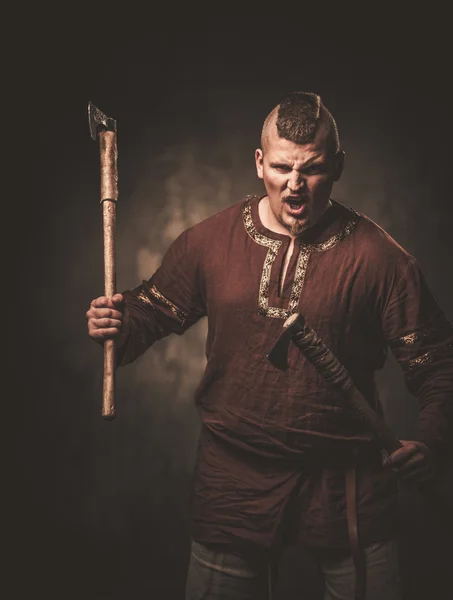 Viking sério com machados em uma roupa de guerreiro tradicional — Fotografia de Stock