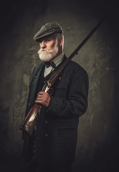 Senior hunter with a shotgun in a traditional shooting clothing — Stock Photo, Image