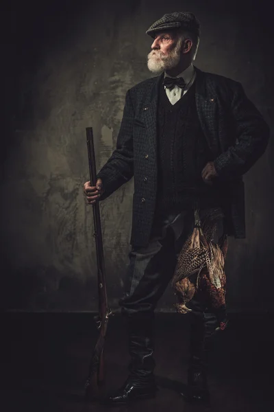 Senior hunter with a shotgun in a traditional shooting clothing — Stock Photo, Image