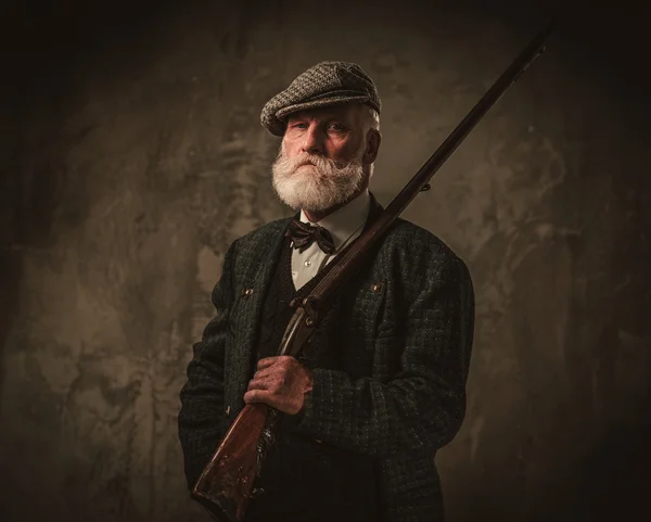 Senior hunter with a shotgun in a traditional shooting clothing — Stock Photo, Image