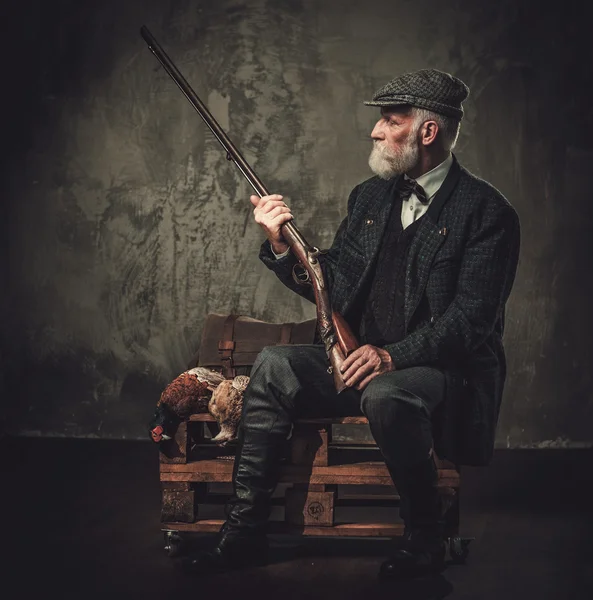 Senior hunter with a shotgun and pheasants in a traditional shooting clothing — Stock Photo, Image