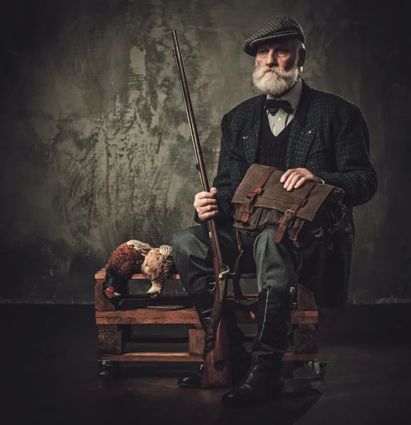 Senior hunter with a shotgun and pheasants in a traditional shooting clothing — Stock Photo, Image