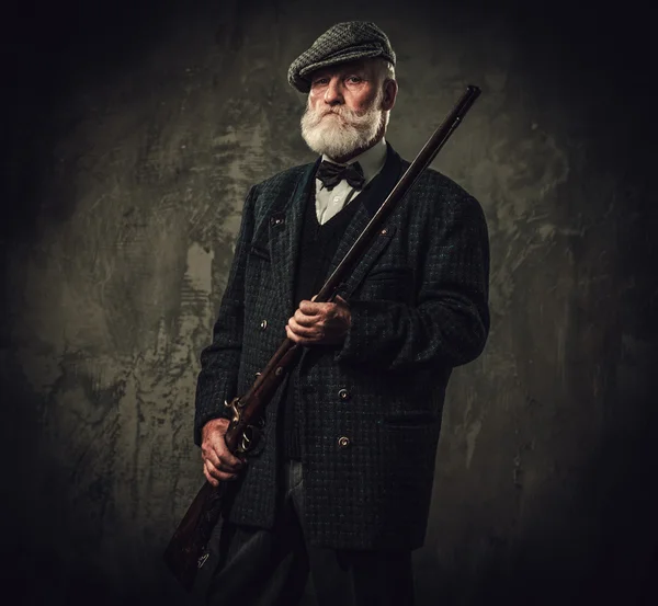 Senior hunter with a shotgun in a traditional shooting clothing — Stock Photo, Image