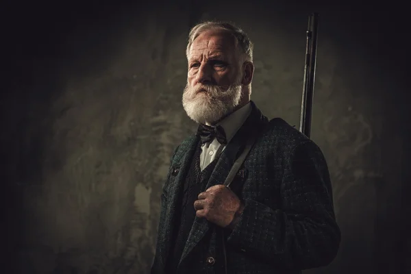 Senior hunter with a shotgun in a traditional shooting clothing — Stock Photo, Image