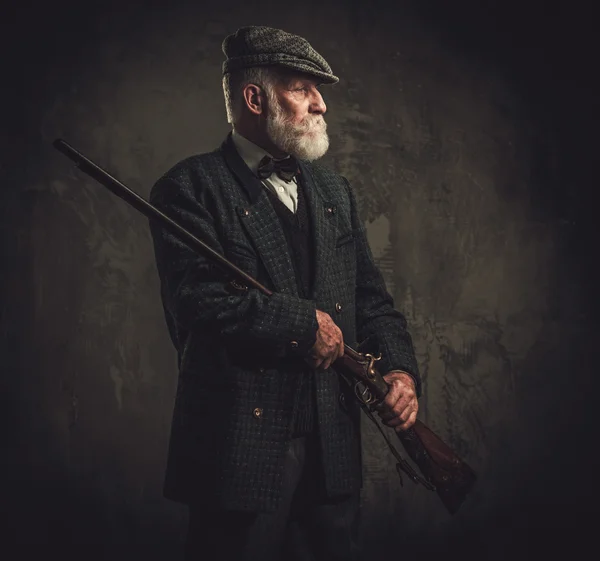 Senior hunter with a shotgun in a traditional shooting clothing — Stock Photo, Image