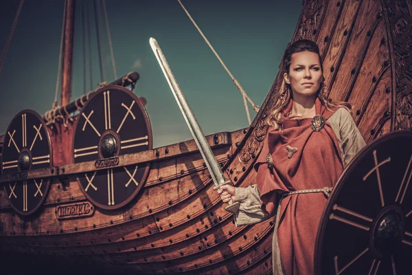 Viking woman with sword and shield standing near Drakkar — Stock Photo, Image