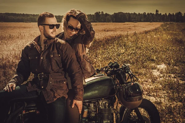 Elegante casal piloto de café na motocicleta personalizada vintage — Fotografia de Stock