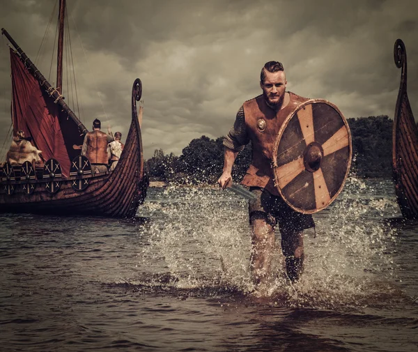 Guerrero vikingo en el ataque, corriendo por la orilla con Drakkar —  Fotos de Stock