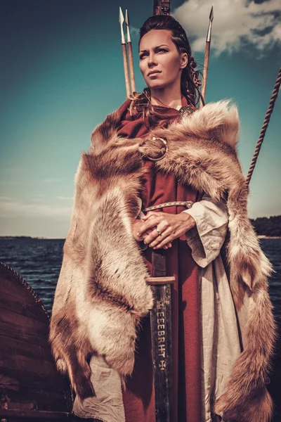 Viking vrouw met zwaard en schild permanent op Drakkar. — Stockfoto