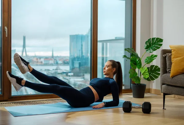 Slender woman practices abdominal exercises on blue mat — 图库照片