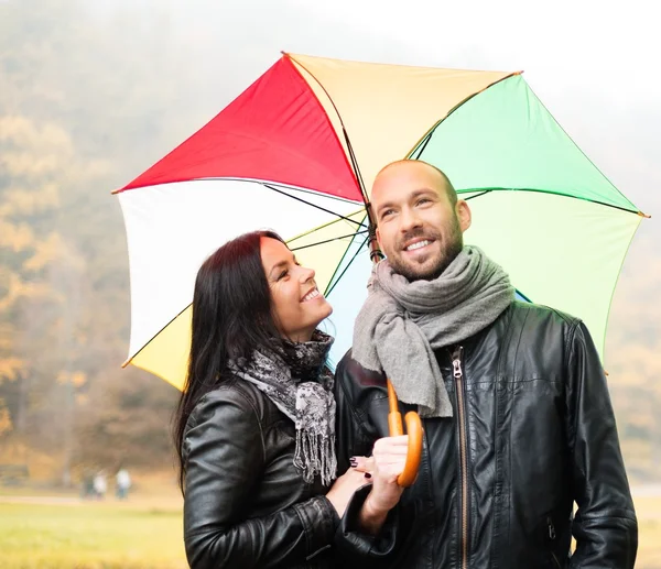 Glückliches Paar mittleren Alters mit Sonnenschirm im Freien an einem schönen regnerischen Herbsttag — Stockfoto