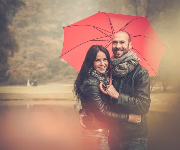 Happy middle-aged couple with umbrella outdoors on beautiful rainy autumn day — Stock Photo, Image