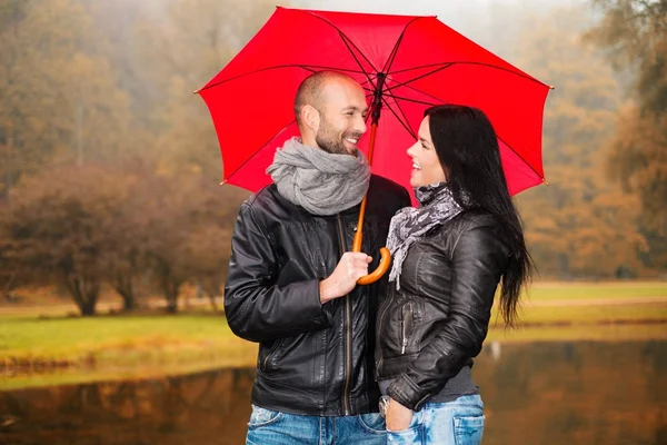 Feliz casal de meia-idade com guarda-chuva ao ar livre no belo dia chuvoso de outono — Fotografia de Stock